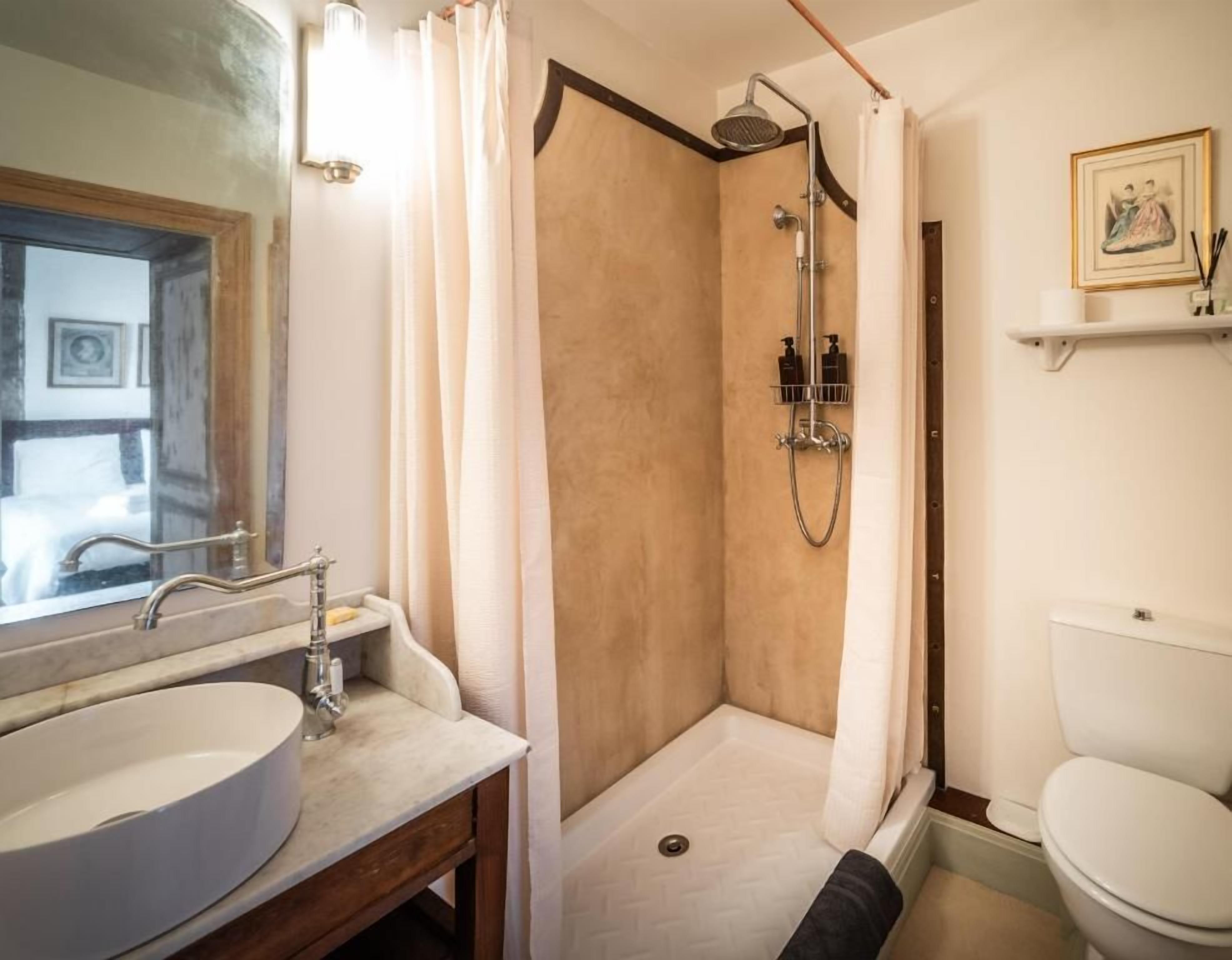 Een badkamer met douche, toilet, wastafel en spiegel.