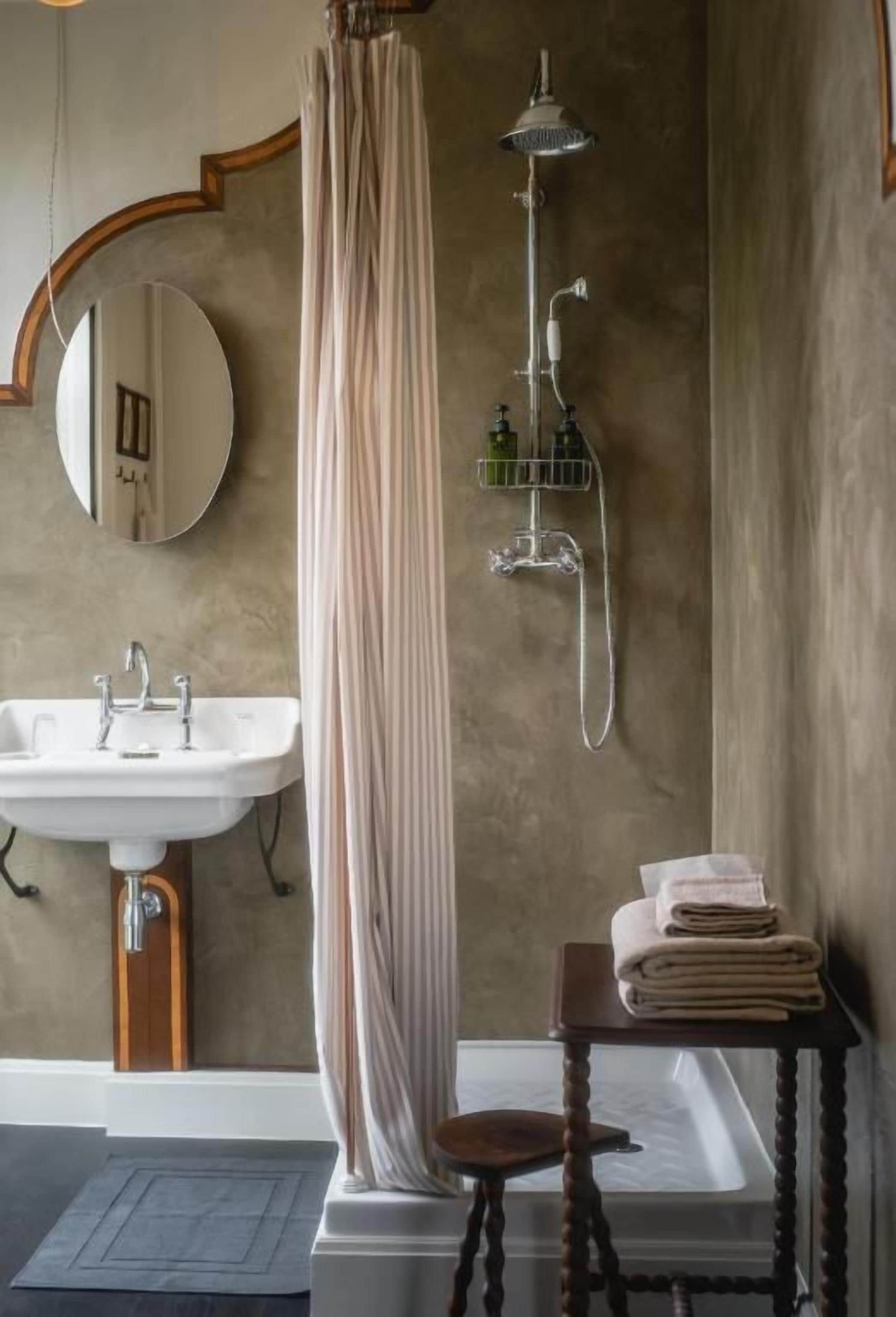 A bathroom with a sink, shower, and a mirror.