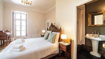A hotel room with a large bed, bedside lamps, a wooden nightstand, a bathroom with a mirror and sink.