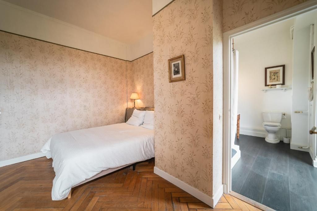 Et soveværelse med seng, et natbord med lampe og en dør til et badeværelse.