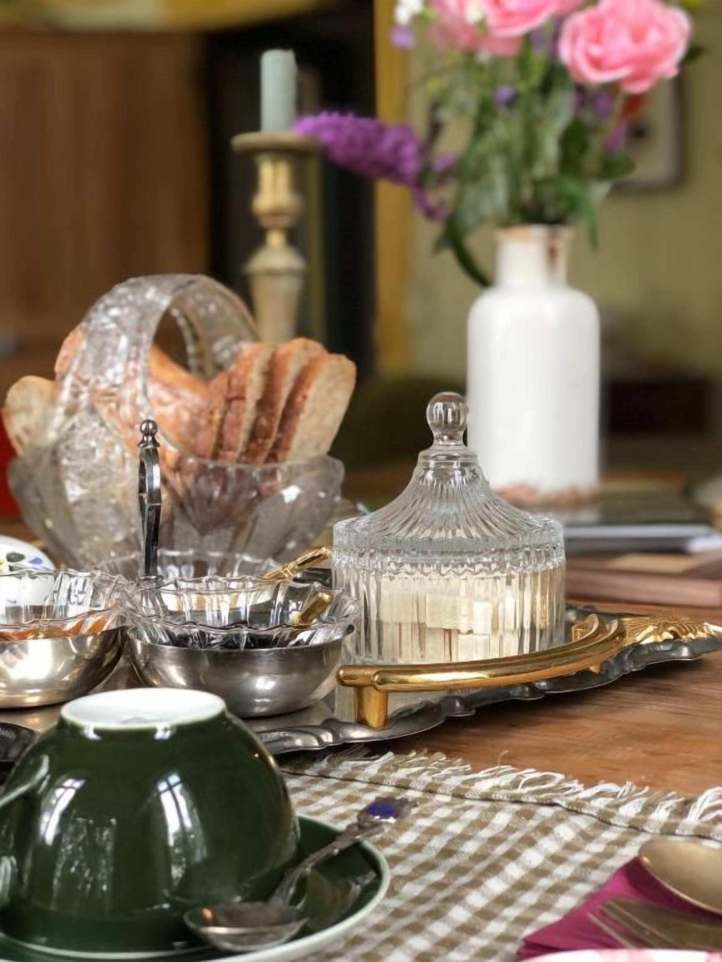 Une table dressée avec différents types de verres, une tasse verte et un plateau avec du pain.