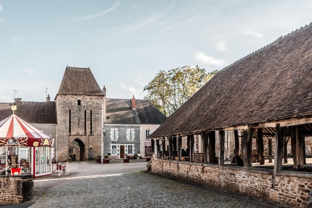 Une rue pavée bordée de bâtiments historiques, une structure en bois couverte et un kiosque à rayures rouges et blanches.