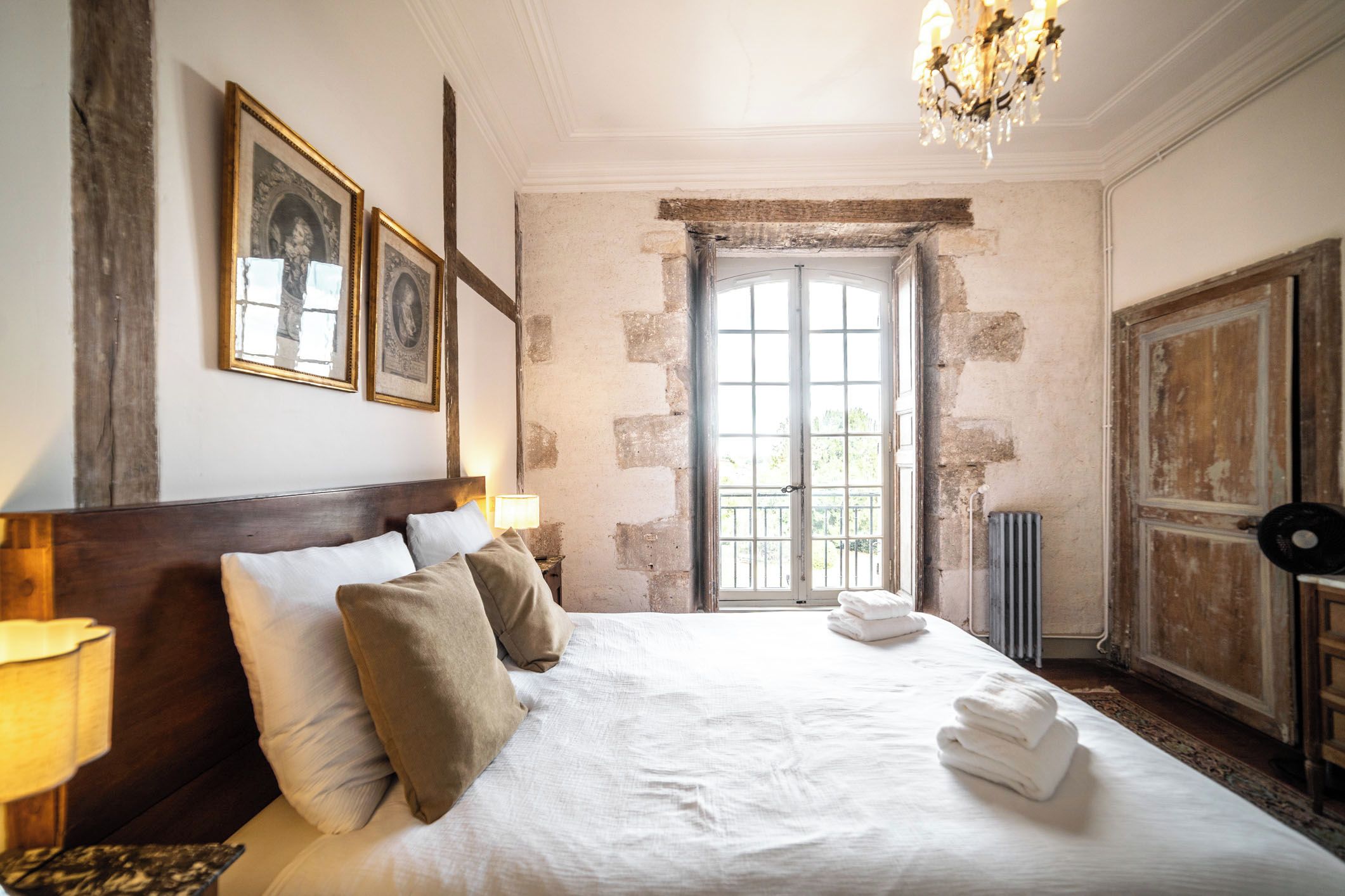 Habitación de hotel con una cama grande, un candelabro, un radiador y vistas por la ventana.