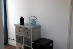 Una habitación con un aparador, una tetera azul y un electrodoméstico negro.