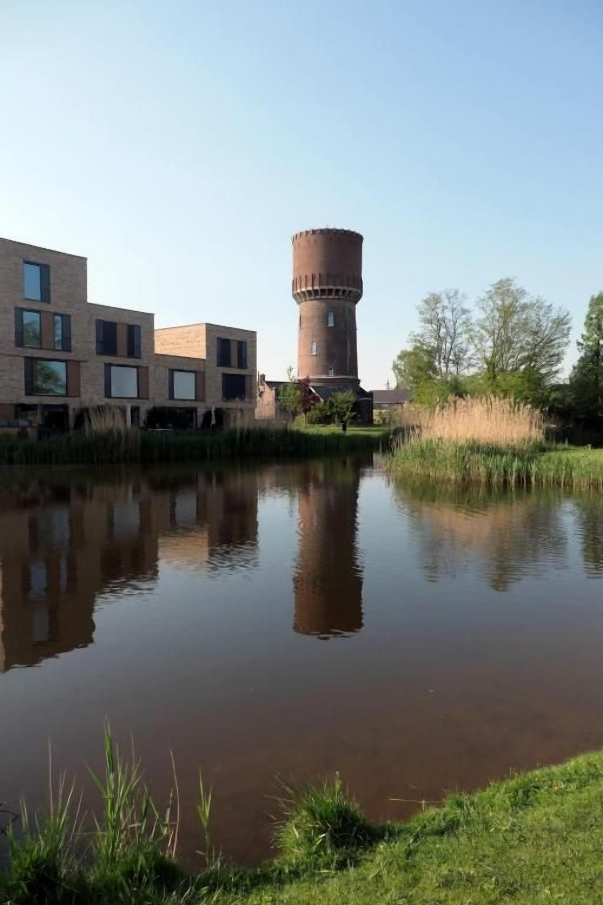Un edificio con un tanque de agua, un estanque y una zona cubierta de césped.