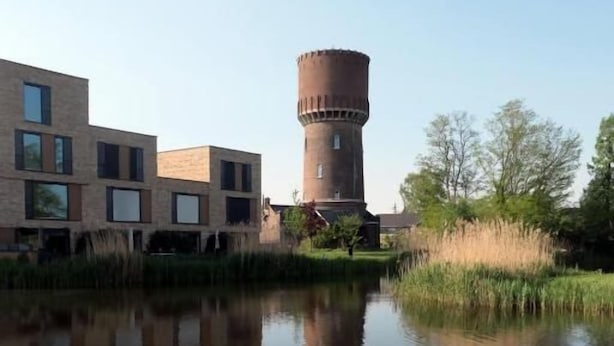 Un edificio con un tanque de agua, un estanque y una zona cubierta de césped.