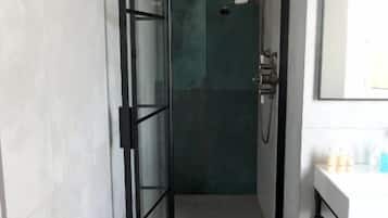Ein modernes Badezimmer mit einer gläsernen Dusche, einem weißen Waschbecken und einem Spiegel darüber.
