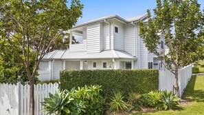 Une maison à deux étages, à l’extérieur blanc, dotée d’un porche avant couvert et d’une clôture en bois peinte en blanc.