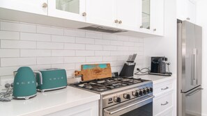 Eine moderne Küche mit weißen Schränken, einem Gasherd, einem Toaster und einem Kühlschrank.