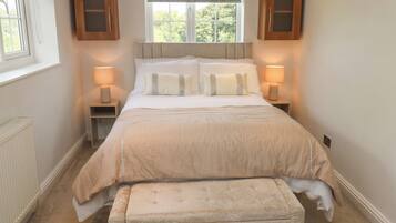 A bedroom with a bed, bedside lamps, a window with a view, and a radiator.