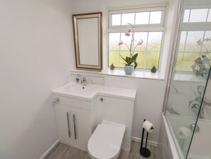 A bathroom with a toilet, bidet, sink, and a window with a view of greenery. - Nabwood Views (Shipley)