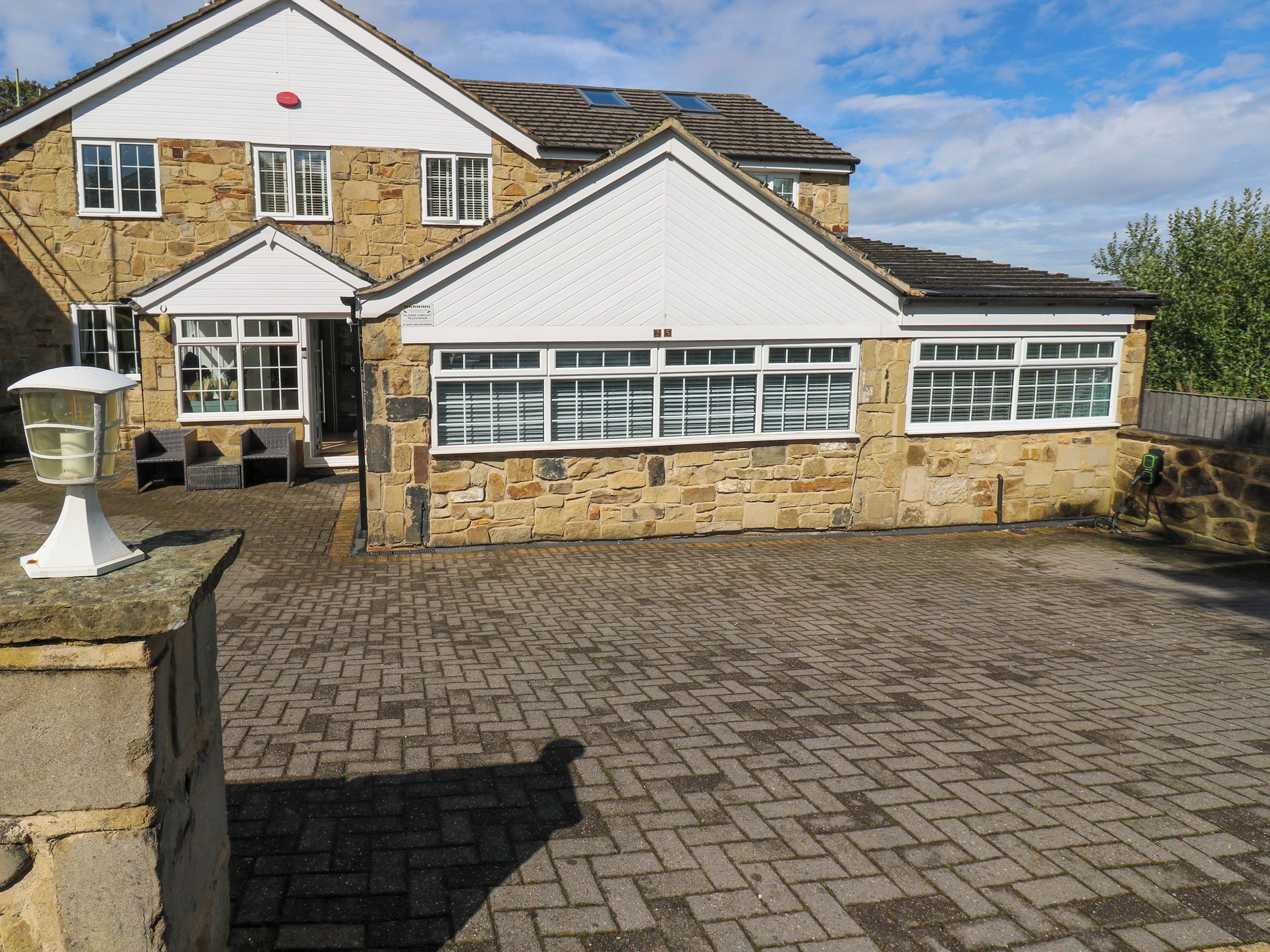 A stone building with a garage, a paved driveway, and a lamp post.