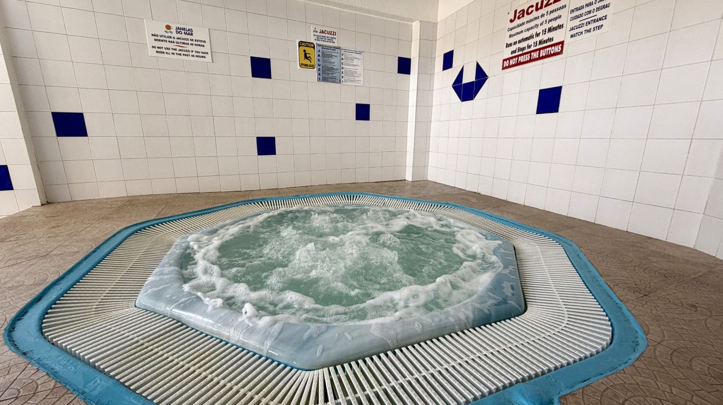 Een whirlpool in een betegelde ruimte met veiligheidssignes op de muren.