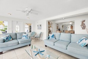 Un salón espacioso con dos sofás azul claro, una mesa de centro de vidrio y estrellas de mar decorativas.