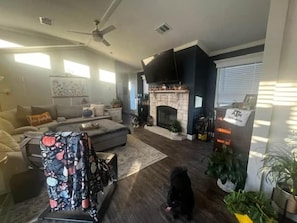 A spacious living room with a fireplace, a large sofa, and a dog.