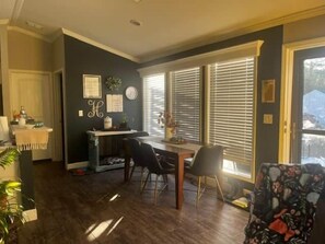 A dining area with a table and chairs, a kitchen area with a counter and appliances, and a door leading to another room.