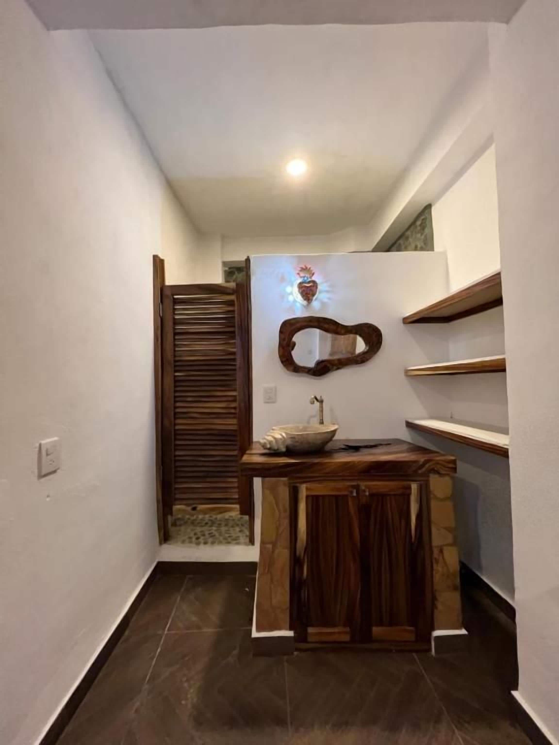 Un pasillo estrecho con un banco de madera y una pequeña mesa con un cuenco.