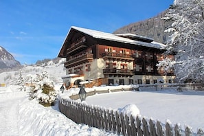 A multi-story chalet with balconies, surrounded by snow-covered trees and a clear sky. - Schlosswirt (Grosskirchheim)