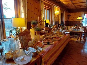 A dining area with a long wooden table set for a meal, surrounded by chairs. - Schlosswirt (Grosskirchheim)