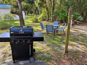 Ein Grillbereich im Freien mit einem tragbaren Gasgrill, einem Esstisch und Stühlen.