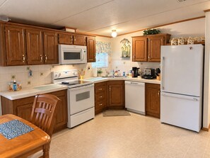 A compact kitchen with wooden cabinets, a microwave, stove, dishwasher, and a refrigerator. - A Little Slice Of Paradise Near World Equestrian Center & Rainbow River (Ocala)