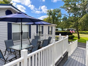 A deck with outdoor furniture and a covered area, surrounded by a white fence. - A Little Slice Of Paradise Near World Equestrian Center & Rainbow River (Ocala)
