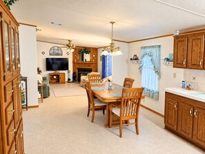 Un ampio soggiorno con camino, zona pranzo con mobili in legno e cucina con pensili in legno.