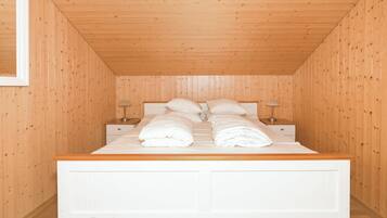 A bedroom with a wooden ceiling, a white bed, and two bedside tables with lamps.