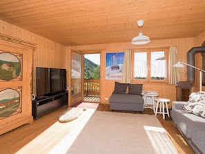 Un interior de madera con televisor, sofá y una pequeña mesa.