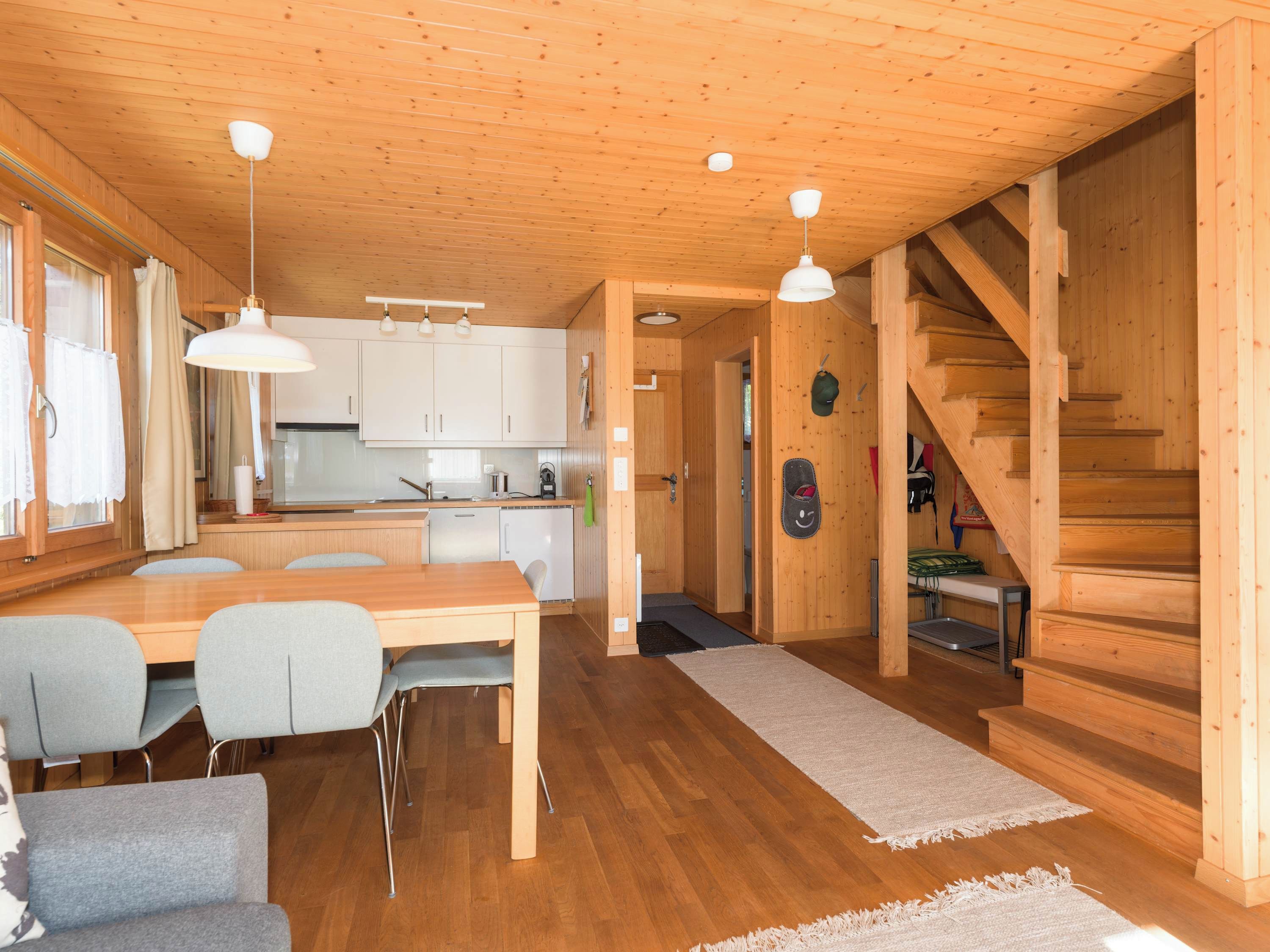 A wooden interior with a dining area, kitchen, and staircase.