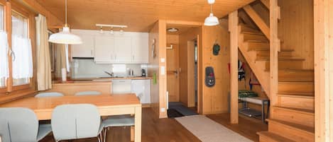 A wooden interior with a dining area, kitchen, and staircase.