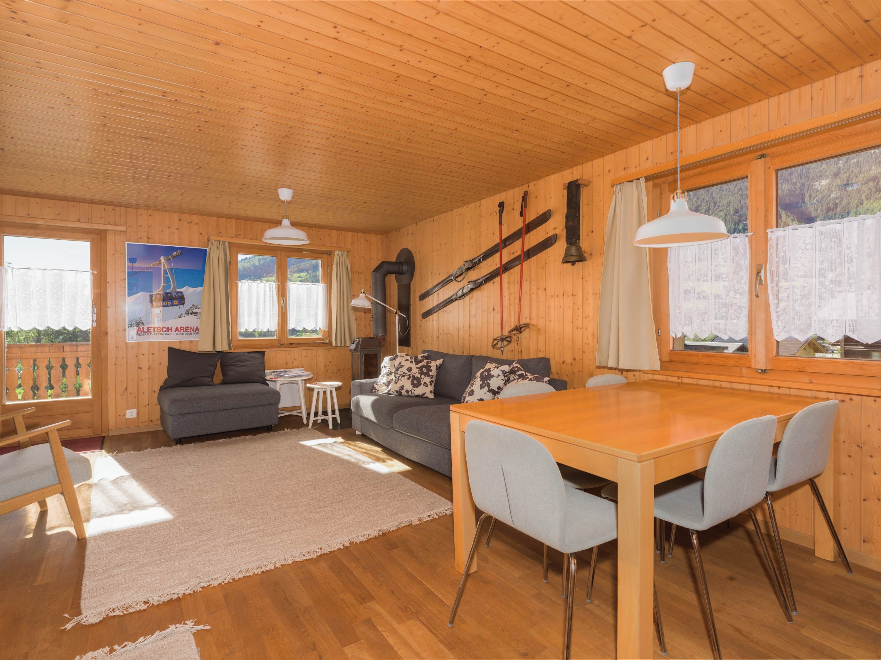 L’intérieur d’un chalet en bois comprend un coin repas, un canapé et du matériel de ski.