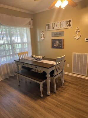 A dining area with a table, chairs, and a wall sign reading 'THE LAKE HOUSE'. - “The Nautical Nest” less than 1 mile to KY lake with boat parking on premises. (Dover)