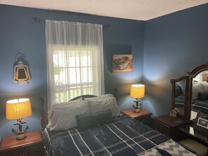 A bedroom with a bed, two bedside lamps, a window with curtains, a wall-mounted lantern, and a framed picture. - “The Nautical Nest” less than 1 mile to KY lake with boat parking on premises. (Dover)