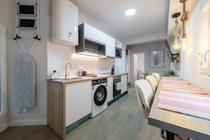 Een praktische keuken met een wasmachine, een magnetron en een fornuis.