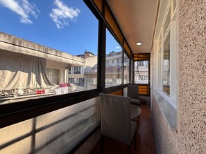A balcony with a view of neighboring buildings, a chair, and a table. - Central 3BR Near Metro and Cevahir (Istanbul)