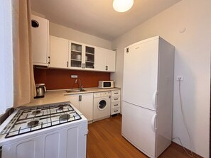 Kompakti keittiö, jossa on kaasuliesi, pesukone, mikroaaltouuni ja jääkaappi.
