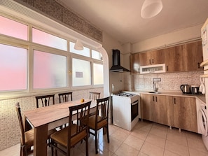 A kitchen with a dining table, chairs, a stove, and cabinets. - Elegant 3BR Stay | Heart of Şişli (Istanbul)