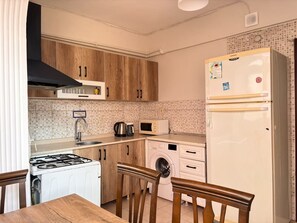 A compact kitchen with a stove, microwave, and washing machine. - Elegant 3BR Stay | Heart of Şişli (Istanbul)