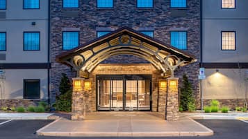 A building entrance with a stone archway, large glass doors, and a parking sign.