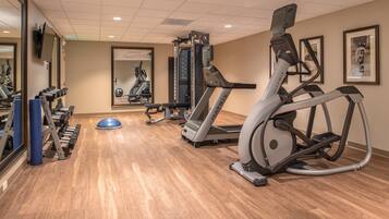 Un gimnasio con cintas de correr, elípticas y pesas sueltas.