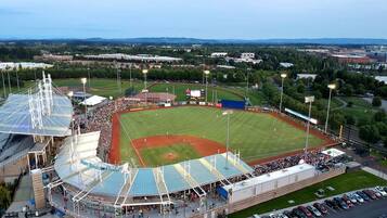 Un stade comprenant un terrain de baseball, des gradins et un parking.