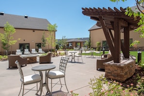 An outdoor patio area with seating arrangements, a pergola, and a stone planter.