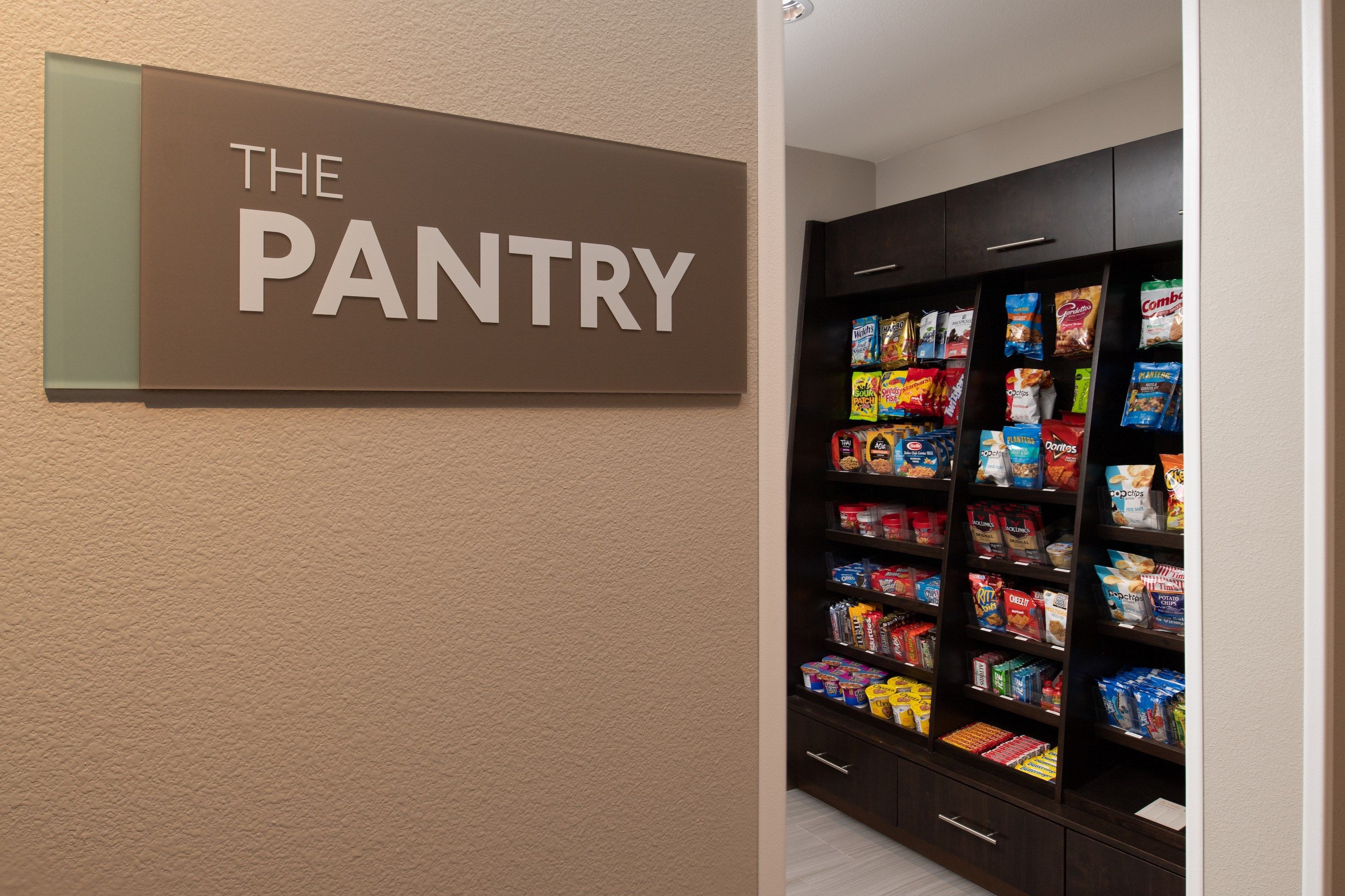 A pantry area with a sign reading "THE PANTRY" and shelves stocked with various snacks and food items.