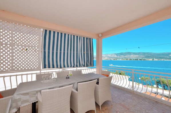 Un balcon avec une table et des chaises, offrant une vue sur la côte.
