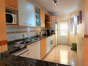 A compact kitchen with a microwave, sink, and stove. - Villa Zen with sea view (Puerto del Carmen)
