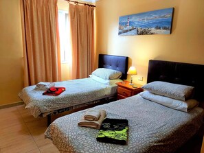 A hotel room with two beds, a painting on the wall, and a window with curtains. - Villa Zen with sea view (Puerto del Carmen)