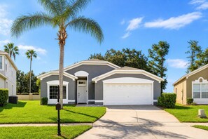 A residential house with a garage, a front yard with grass, and a palm tree. - Heated Pool~Windsor Resort~Near Disney~Game Room (Kissimmee)