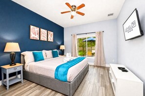 A bedroom with a bed, nightstands, a desk, a ceiling fan, and artwork on the wall. - Heated Pool~Windsor Resort~Near Disney~Game Room (Kissimmee)