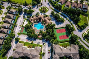 An aerial view of a residential area with a central swimming pool, tennis courts, and a landscaped park area. - Heated Pool~Windsor Resort~Near Disney~Game Room (Kissimmee)